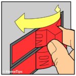 Man’s fingers holding a red circuit breaker switch, including an arrow pointing to a direction.