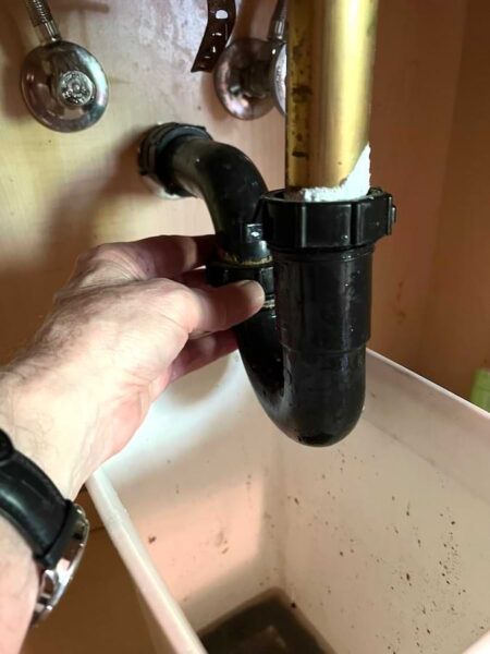 Tightening sink trap coupling nuts beneath a sink